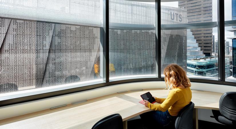 A desk with a view over Broadway and the UTS campus, within the UTS Graduate School of Health